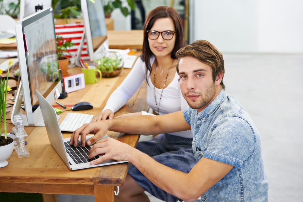 Two young tech entrepreneurs working together in a modern office, collaborating on a project